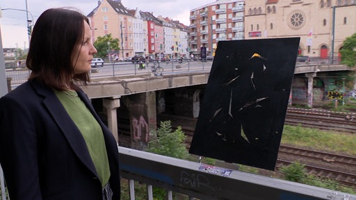 Das Bild zeigt Sabine Reimann neben dem Kunstwerk der Erinnerung.