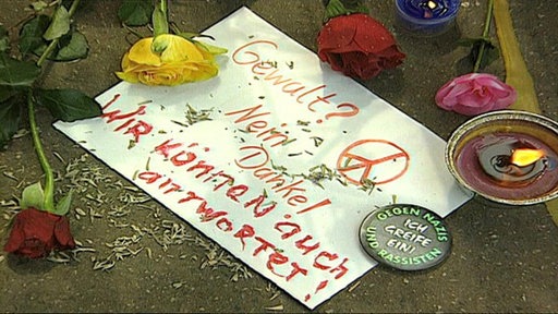 Schild liegt auf dem Boden mit Rosen drumherum 