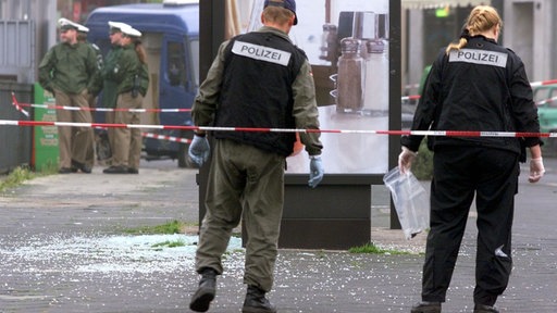 Polizisten stehen hinter Flatterband