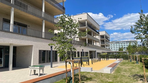 Das neue Gymnasium an der Brügelmannstraße von außen mit Grünflächen und einem Tischkicker 