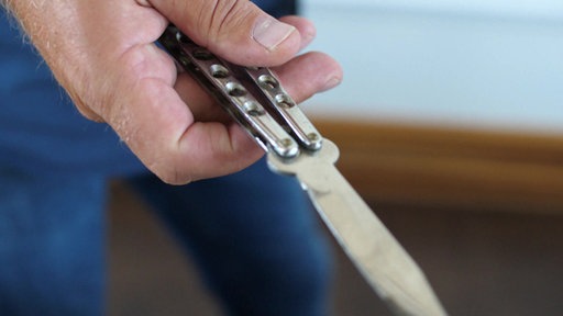 Ein Klappmesser wird symbolisch in der Hand gehalten. Auseinandersetzungen mit Stichwaffen im öffentlichen Raum kommen immer wieder vor.