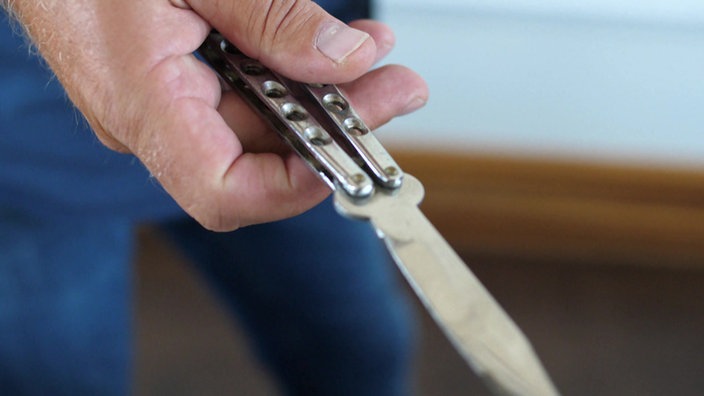 Ein Klappmesser wird symbolisch in der Hand gehalten. Auseinandersetzungen mit Stichwaffen im öffentlichen Raum kommen immer wieder vor.