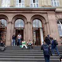 Studierende sitzen auf der Treppe am Eingang zum Hauptgebäude der RWTH Aachen.