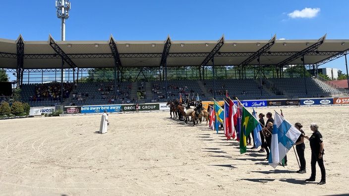 Innenraum vom Dressurstadion mit Pferden und Fahnenträgern in einer Reihe aufgestellt