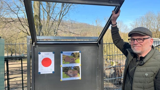 Tierparkleiter lächelt und zeigt Entwürfe für neues Haus