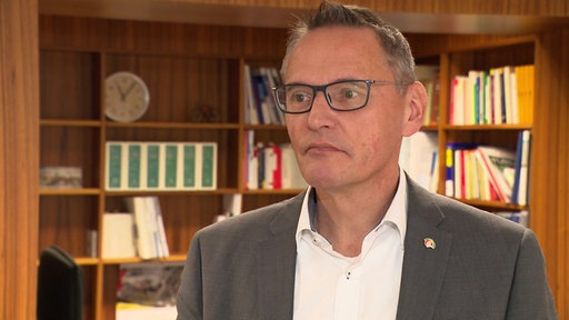 Ein Mann im Anzug vor einem Bücherregal