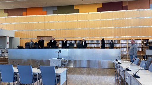 Menschen in Gerichtsroben stehen auf einem Podest hinter einem langen Tisch