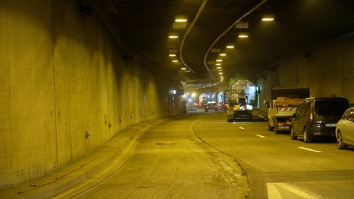 Neuer Asphalt im Tunnel, Baustellenfahrzeuge stehen rechts, links eine leere Fahrbahn