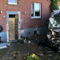 Eine beschädigtes Backsteinhaus. Daneben ein Auto mit kaputter Front.