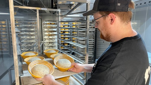 Ein Bäcker schaut sich Schüsseln voller Brot-Teig an