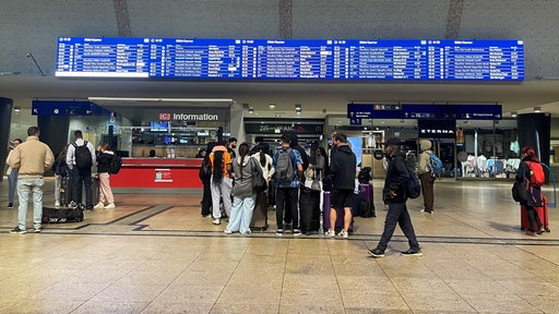 Blick auf die Anzeigetafel im Kölner Hauptbahnhof an einem frühen Montagmorgen, mehrere Menschen stehen davor