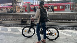 Bernadette Blob, Bahnpendlerin, steht mit ihrem Fahrrad auf einem Bahnsteig
