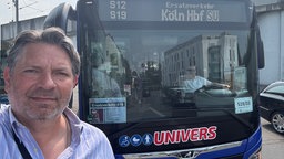 Mann steht vor einem Bus mit der Anzeige "S12 Ersatzverkehr - S19 Köln HBF"