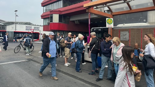 Viele Menschen stehen an einer Bushaltestelle