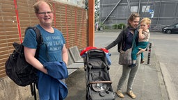 Ein Mann und eine Frau mit Kinderwagen - die Frau trägt ein Kleinkind auf dem Arm