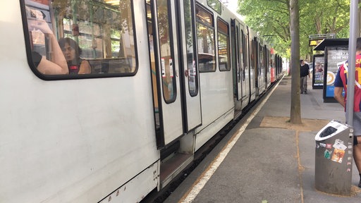 Eine Straßenbahn an einer Haltestelle, der Einstieg ist nur mit Stufen möglich