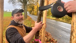 Jörn Riemann befestigt eine Stütze für einen neu gepflanzten Baum