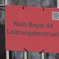 Ein rotes Schild mit der Aufschrift "Kein Bayer 04 Leistungszentrum!"