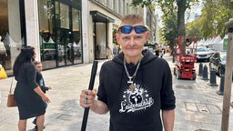 Auf dem Bild sieht man den ehemaligen Obdachlosen Sven, der einen Besen in der Hand hält