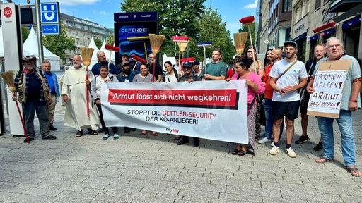 Bettler und Unterstützer des Protests, die Besen in die Luft halten