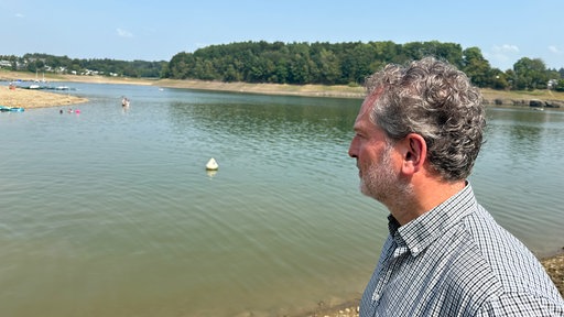 Ein mann schaut nachdenklich in die Ferne. Im Hintegrund ist die Bevertalsperre zu sehen