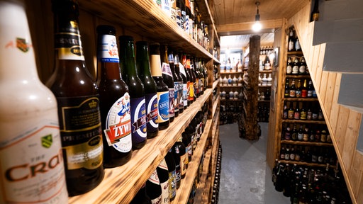 Ein Bier steht neben dem anderen in Regalen im Keller.