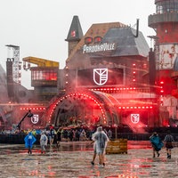 Die New Bill's Factory, eine Bühne beim Parookaville-Festival in Weeze, mit Menschen, die mit Ponchos durch den Regen laufen