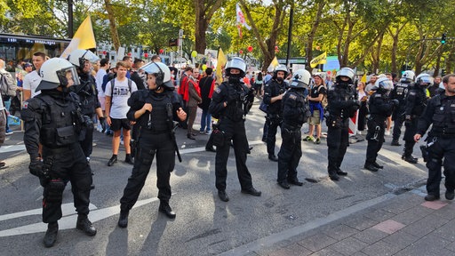 Polizisten bilden eine Reihe um zwei Gruppen voneinander zu trennen