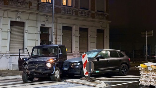 Ein von einem Kombi gerammter SUV mit Lateralschäden steht auf einer nächtlichen Straße