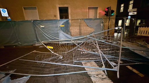 Ein stark lädiertes Absperrgitter liegt auf einer nächtlichen Straße