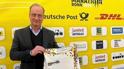 MMP-Geschäftsführer Christian Okon zeigt das bunte Sondertrikot zum diesjährigen Marathon