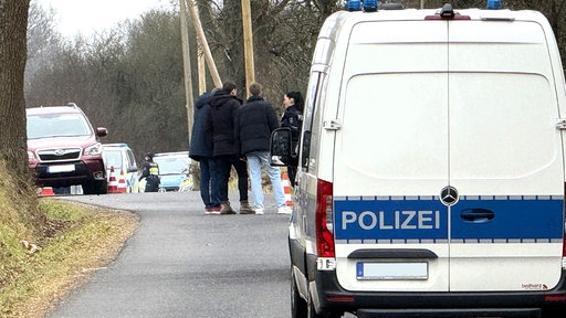 Einsatzfahrzeuge der Polizei auf einer Straße durch den Wald.
