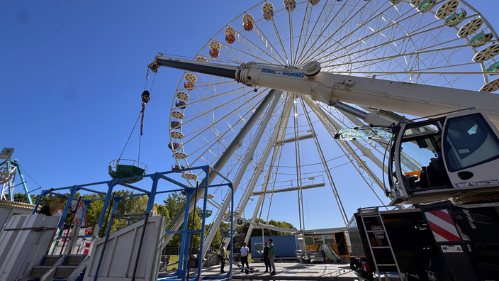 Mit einem Autokran werden die vielen Gondeln am Riesenrad befestigt.
