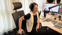 Eine Frau sitzt in einem Aufnahmestudio vor einem Mikrofon
