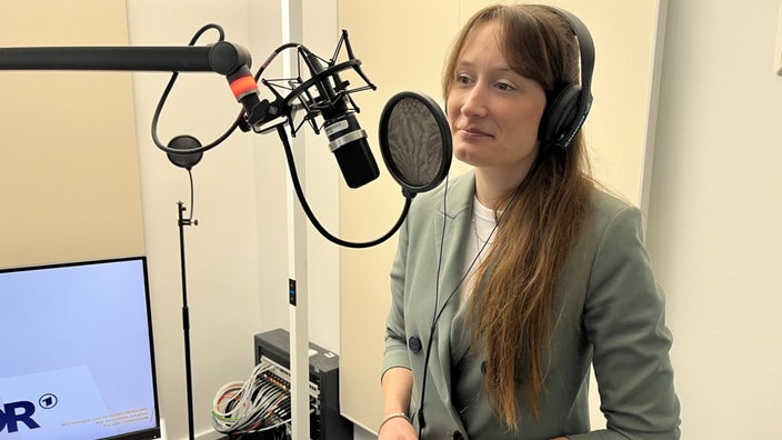 Friederike Schaffrath steht in einem Aufnahmestudio vor einem Mikrofon