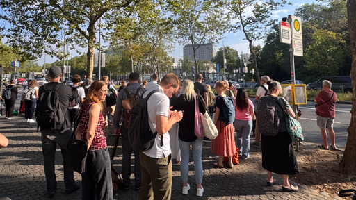 Viele Personen stehen an der Haltestelle der Heussallee in Bonn