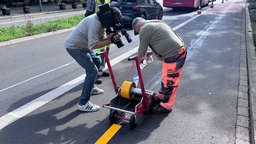 Ein Kameramann filmt einen Mitarbeiter der Stadt bei Markierungsarbeiten