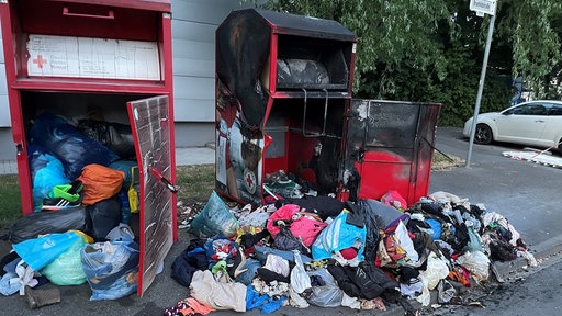 Eine große Menge Altkleider vor Altkleidercontainern