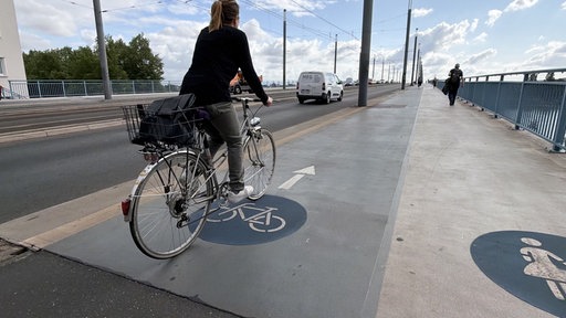 Eine Fahrradfahrerin fährt über die Kennedybrücke in Bonn