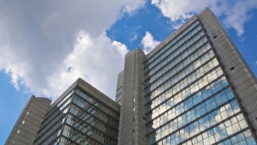 Das Bonner Stadthaus aus der Froschperspektive. Der Himmel ist blau mit ein paar Wolken.