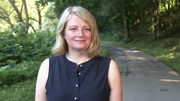 Eine Frau mit blonden Haaren blickt zufrieden in die Kamera.