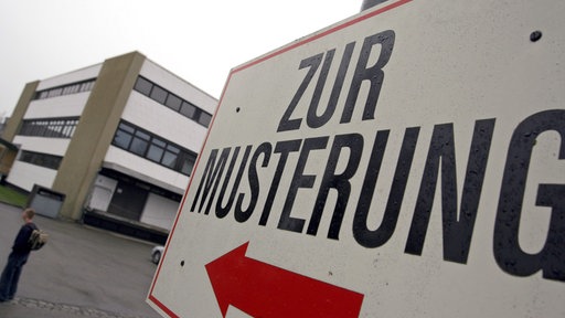 Schild mit der Aufschrift zur Musterung vor einem mehrstöckigen Gebäude