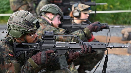 Soldaten in Tarnkleidung zielen mit Waffen