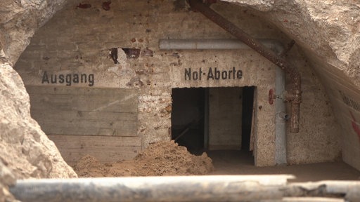 Ausschnitt aus dem Bunker mit den Aufschriften "Ausgang" und "Not-Aborte" an der Wand 