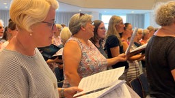 Sopransängerin mit Notenblättern bei der Chorprobe