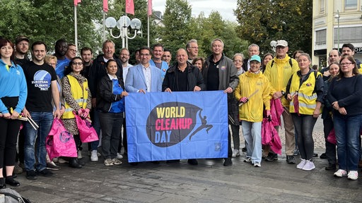 Viele Menschen für den World Cleanup Day in Bonn, blaue Fahne im Vordergrund