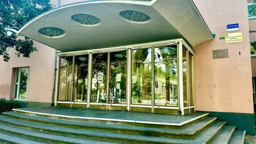 Treppe und mehrere Glastüren, in denen sich Bäume spiegeln