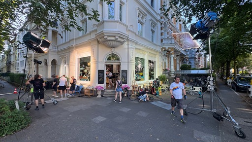 Vor einem Eckhaus aus derGründerzeit stehen Scheinwerfer und viele Menschen wuseln zwischen Kabeln herum.