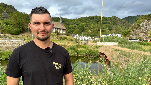 Mann mit schwarzem T-Shirt vor Ufer der Ahr und Kirche im Hintergrund