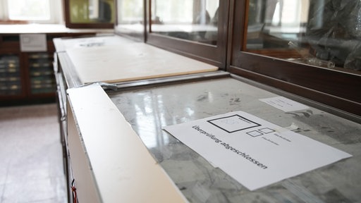 Holzplatten decken zerstörte Glasscheiben in den Vitrinen ab, alles ist voller Staub